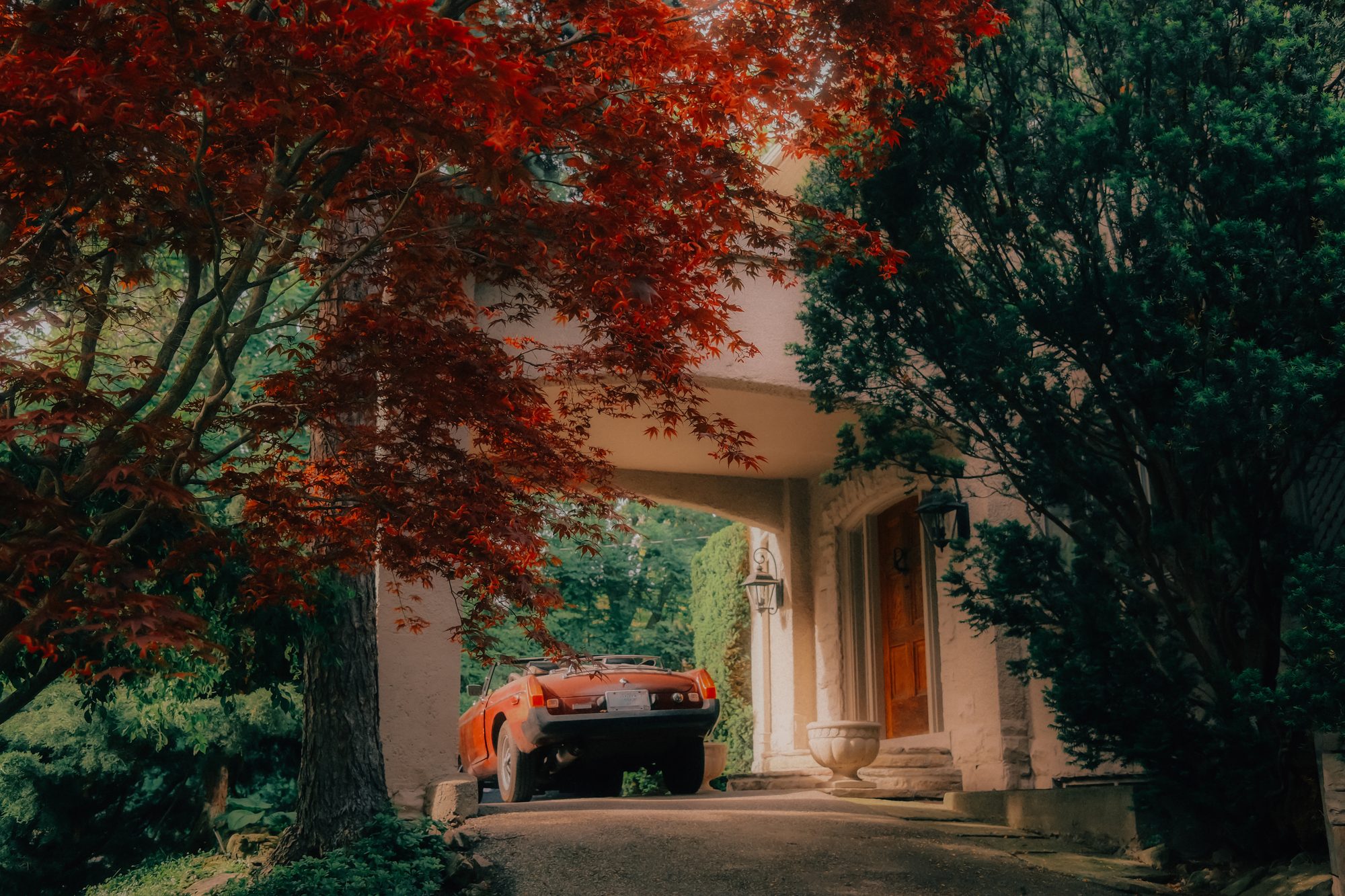 No. 1 — The Porte-Cochère, photograph of a red maple tree and vintage orange car through a stone archway, Toronto