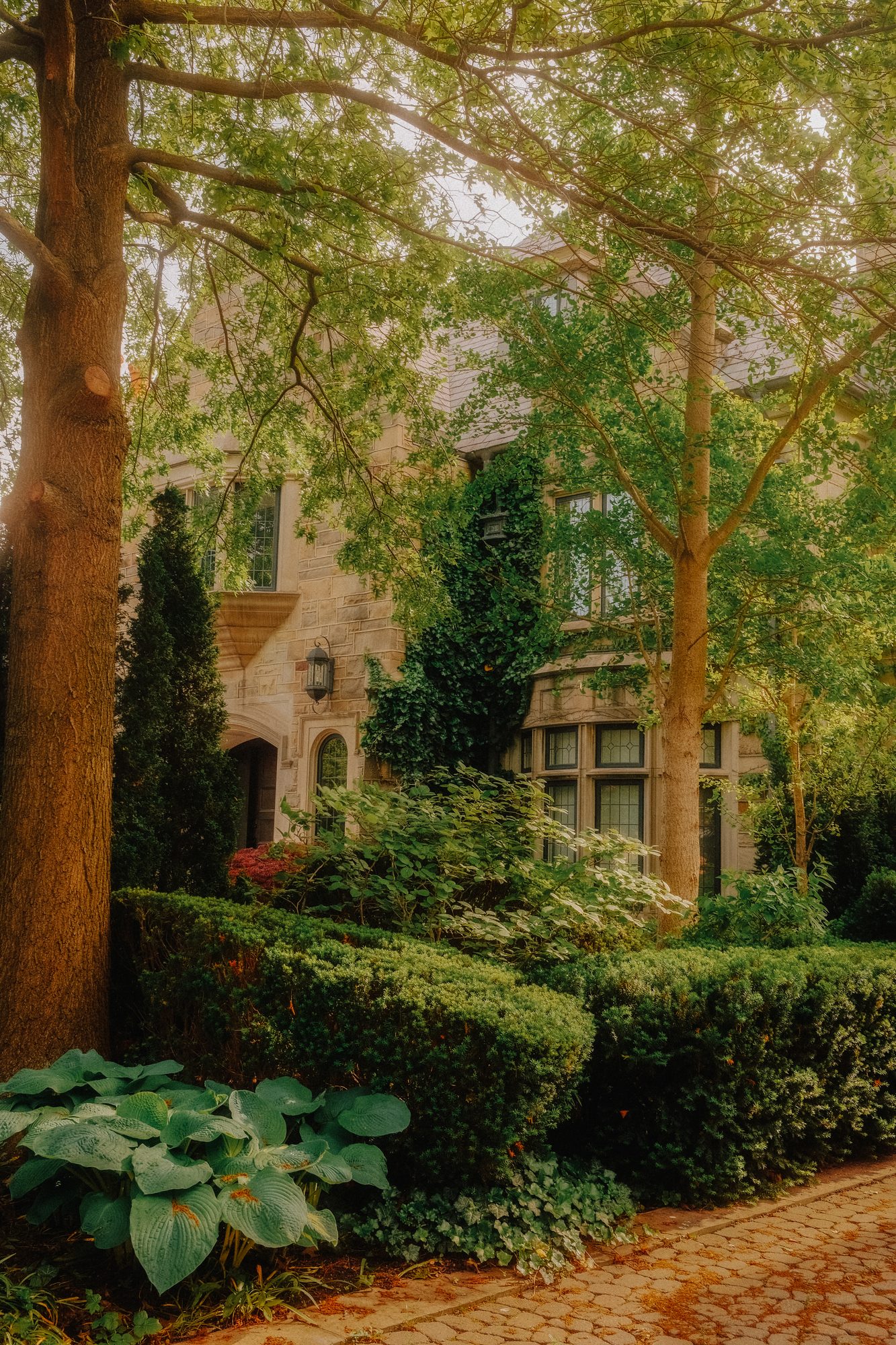 No. 3 — The Manor, photograph of a lush garden estate with manicured hedges and brick path, Toronto